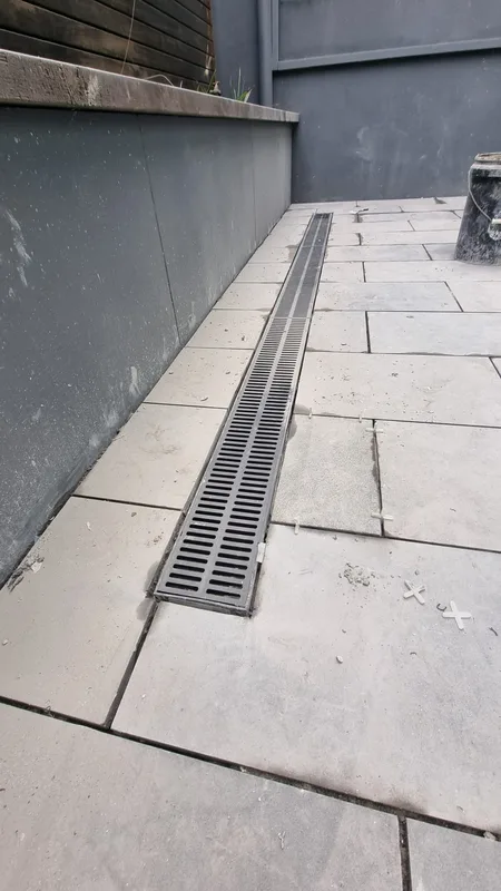 Grated drainage channel set flush with new bluestone paving