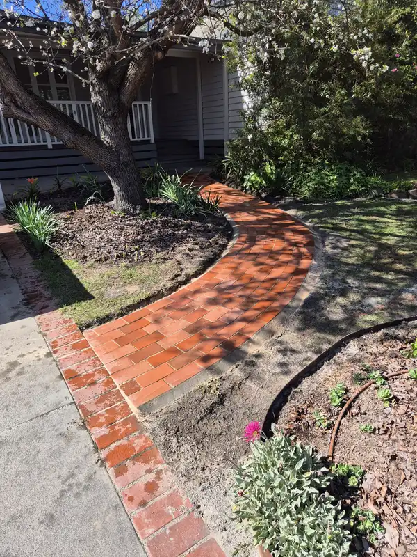 Curved brick path joining a straight brick path in a garden