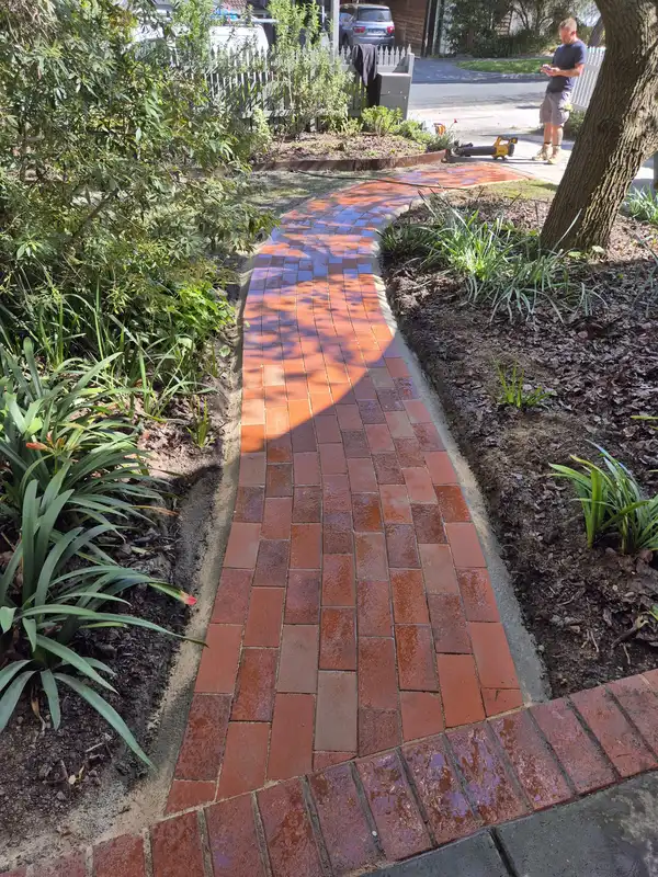 Curved red brick pathway with a concrete haunch edge