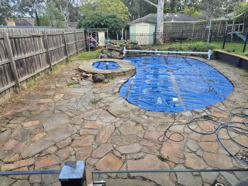 Old crazy paving around a kidney-shaped pool before renovation