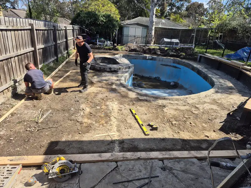 Paving team setting out levels around a pool after removing the old paving
