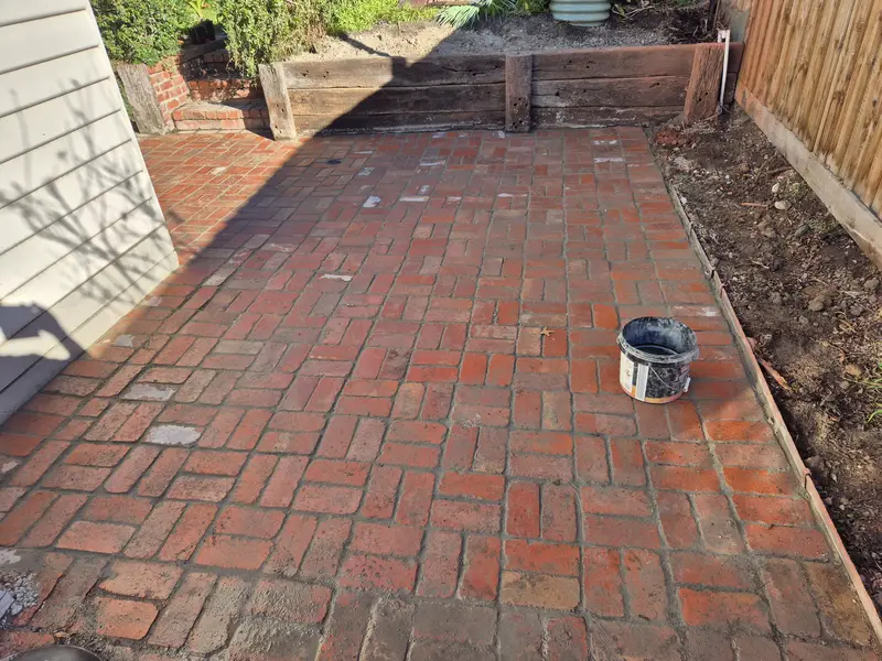 Recycled brick backyard paving with a timber sleeper retaining wall