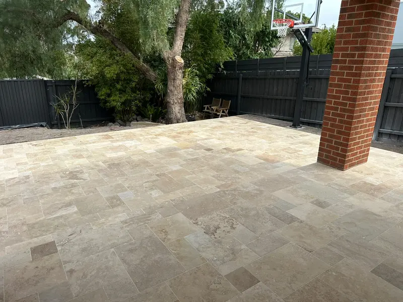 Travertine alfresco patio beside a red brick column