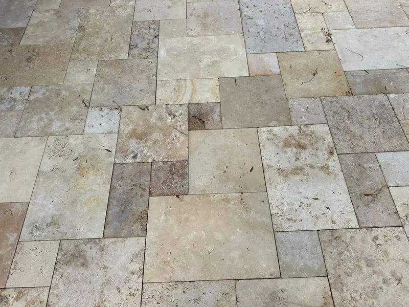 Close-up of tumbled travertine pavers laid in French pattern