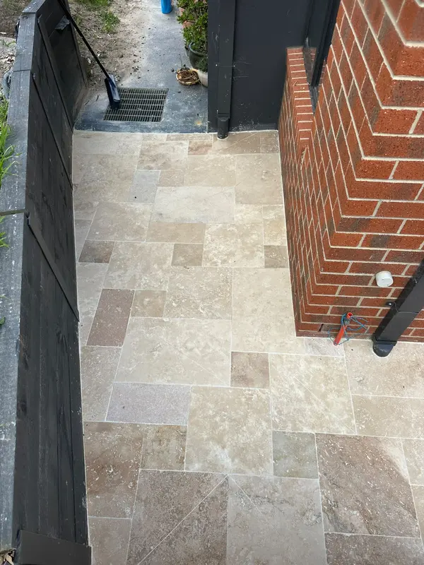 Travertine courtyard paving along a black Colorbond fence