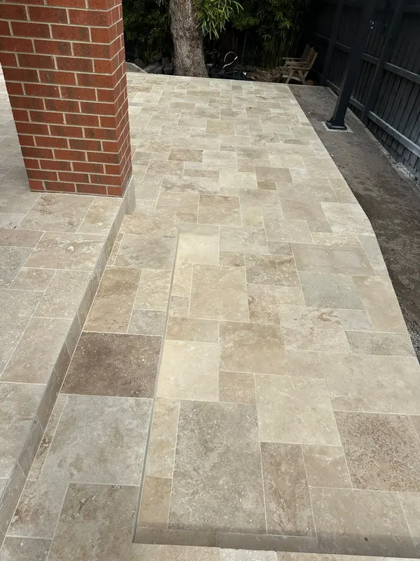 Travertine paving continued along a side path next to a brick home