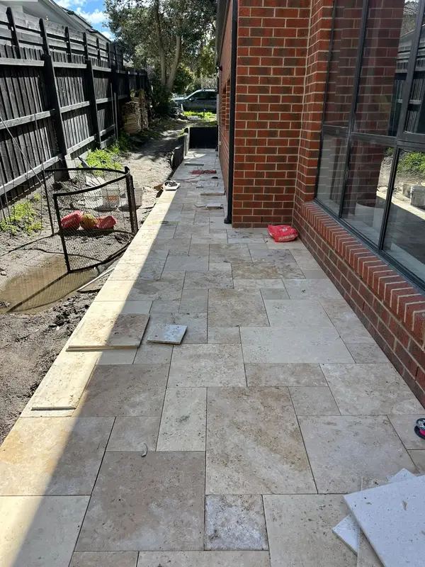 Travertine walkway beside a brick home